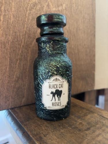 Black cat hisses potion bottle